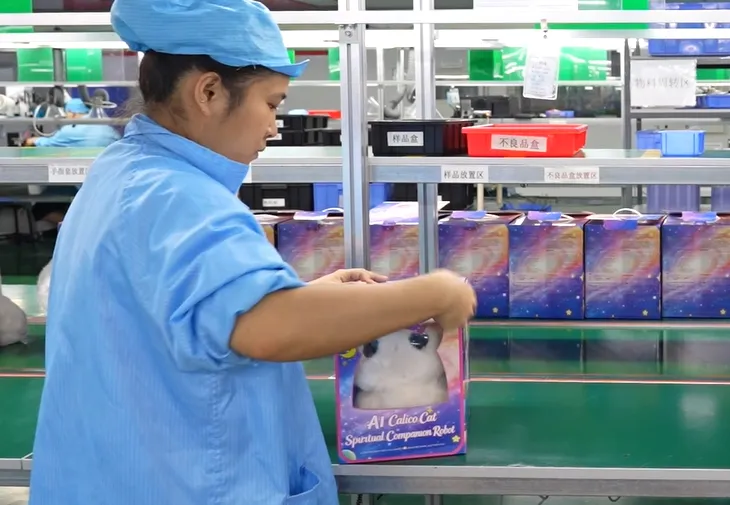生産ラインでAI玩具の販売用パッケージを整える作業員